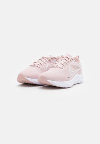 Zapatillas deportivas de color rosa claro con parte superior de malla, detalle texturizado, logo Swoosh blanco, collar acolchado y media suela blanca. Suela de goma para tracción.
