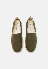 Zelene platnene cipele na slip-on s teksturiranim završetkom, elastičnim bočnim panelima i prirodnim konopljenim đonom. Brend vidljiv na ulošcima.