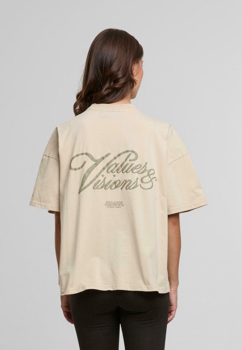 Beige oversized t-skjorte med korte ermer, med et grønt grafisk trykk på ryggen som sier "Verdier & Visjoner" og "Pegador."