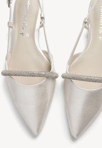 Stříbrné saténové boty s špičatou špičkou a elegantním plochým designem, s perlovým pásem přes nárt. Hladká textura a jemný lesk.
