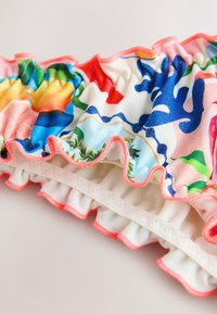 Kleurrijke zwempakstof met geplooide ruches, levendige bloemmotieven, een zachte textuur, een elastische band met een roze bies en een gladde binnenvoering.