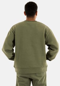 Sudadera verde oliva con cuello redondo, puños y dobladillo acanalados. Con una textura suave y lisa y un ajuste relajado.