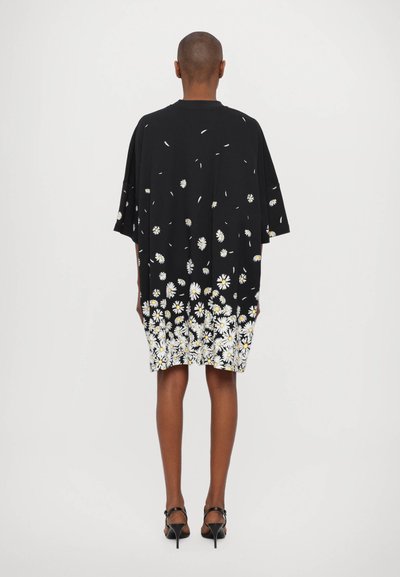 Sort oversized kjole med blomsterlågprint ved kanten, korte ærmer, blødt stof og en afslappet silhuet.