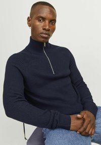Navy gestreifter Strickpullover mit hohem Kragen und halbem Reißverschluss vorne. Verfügt über lange Ärmel und eine taillierte Passform. Glatte Textur, lässiger Stil.