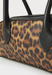 Leopard print handbag with a black leather trim and handles. Features a soft texture and distinct spotted pattern.