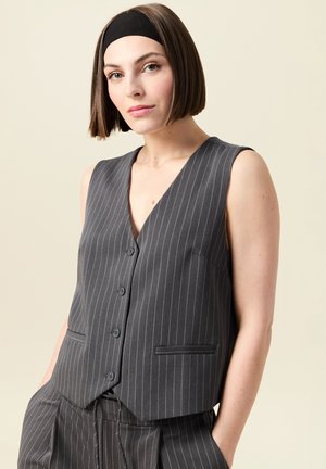 Gilet grigio a righe sottili con scollatura a V profonda, cinque bottoni e tasche laterali. Realizzato in tessuto liscio, presenta un design sartoriale e aderente.