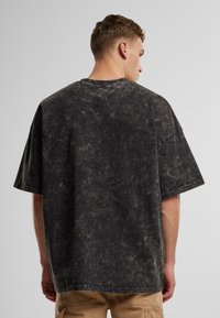 Overdimensioneret T-shirt med korte ærmer i mørkegrå med en tekstureret, marmoragtig finish. Rund halsudskæring og sænkede skuldre forbedrer den afslappede pasform.