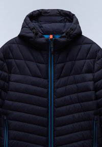 Marine quiltet jakke med blå detaljer, høy krage, hel glidelås og justerbar snorhette. Har glidelås-lommer på sidene.