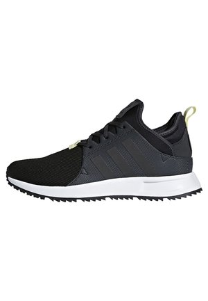 Czarno-szare niskie sneakersy z białą podeszwą, czarnymi sznurówkami, teksturowaną cholewką z tkaniny oraz jasnok żółtą pętlą na pięcie.