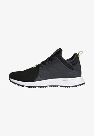 Sneaker bassa nera e grigia con suola bianca, lacci neri, tomaia in tessuto strutturato e linguetta giallo chiaro sul tallone.