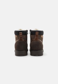 Stivali alla caviglia in suede marrone con parte superiore in sintetico nero, fodera in pelliccia, dettagli in pelle marrone e suole in gomma. Cerniera laterale per una facile vestibilità.