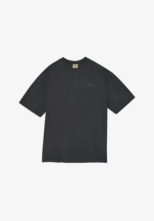 Zwart T-shirt met korte mouwen en een ronde hals, met kleine blauwe tekst "HALO 1968197 1&1" op de linkerborst en een beige label aan de binnenkant van de kraag.