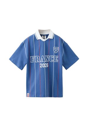 Polo bleu à manches courtes avec col blanc, rayures verticales rouges et blanches, texte "FRANCE 2026" et un emblème en forme de blason avec fleur-de-lis.