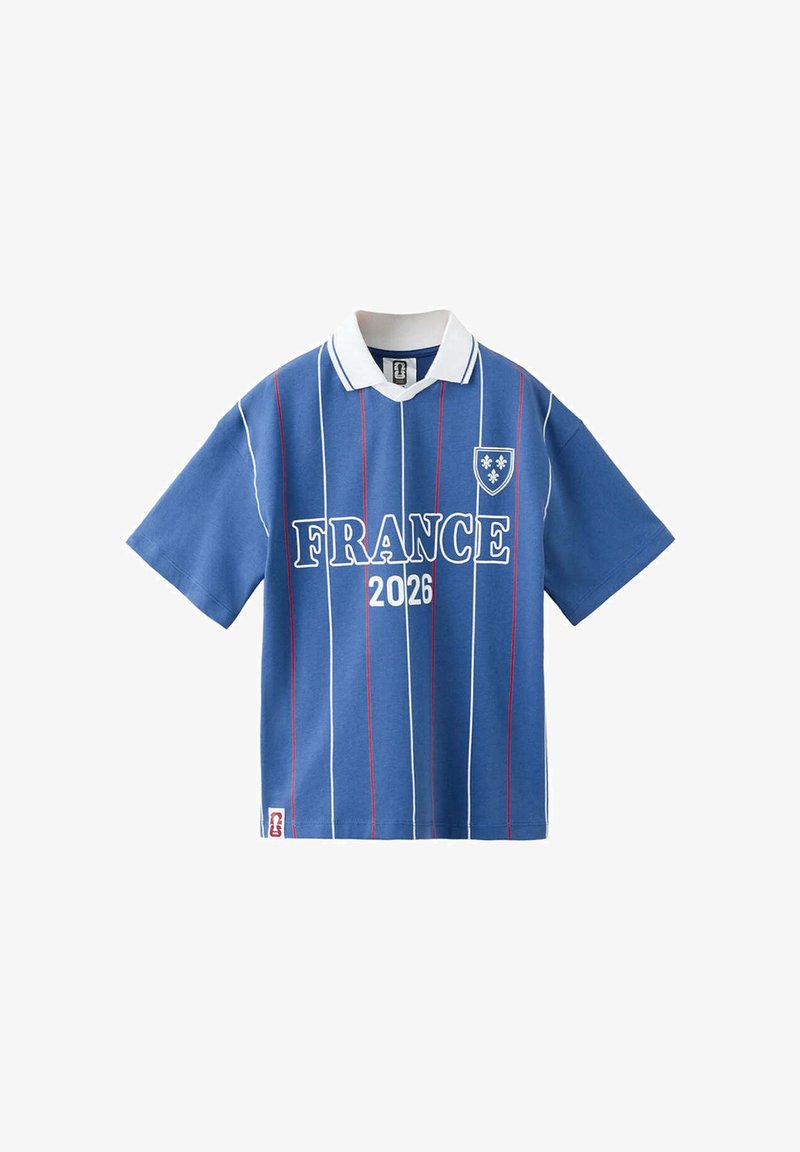 Polo bleu à manches courtes avec col blanc, rayures verticales rouges et blanches, texte "FRANCE 2026" et un emblème en forme de blason avec fleur-de-lis.