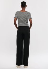 Gestreept zwart-wit shirt met korte mouwen, gecombineerd met hoogwaist zwarte broek met een losse fit en achterzakken.