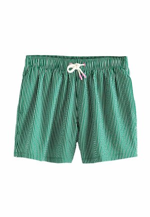 Prim-plan cu pantaloni de baie verzi și albi cu dungi verticale legați cu un șnur alb în talia unei persoane.