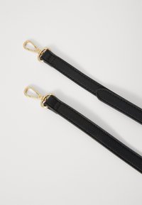 Schwarzes Lederarmband mit strukturiertem Finish und Beschlägen in Goldfarbe. Es hat ein flaches Design mit Stichdetails entlang der Kanten.