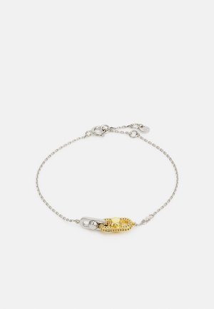 Silver chain bracelet featuring a gold-tone safety pin design with circular accents and textured detailing. Adjustable clasp for size.