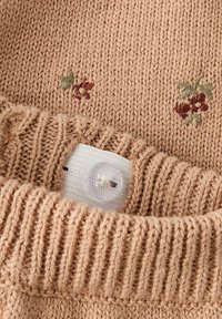 Taanes toonis kootud kampsun, millel on soonikkoes kaelus, punase ja rohelise toonis lillemustriga tikand ning plastiknööp aasaga kinnituseks.