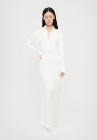 Witte jurk met lange mouwen en kraag, met een voorknopsluiting en een aangesloten silhouet, gemaakt van gladde stof met een lichte glans.
