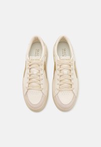 Sneakers beige con lacci, tomaia in pelle, colletto imbottito, punta forata e pannello a contrasto. Suola testurizzata con accentuazioni chiare.