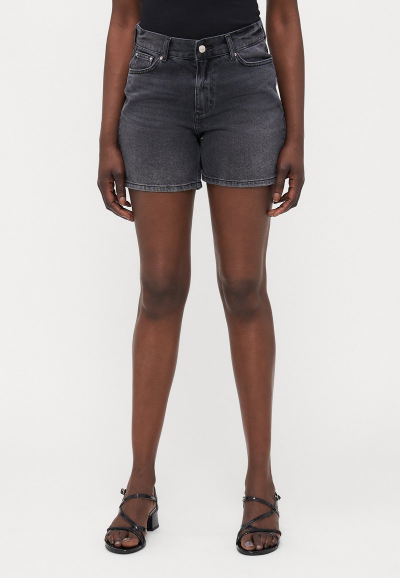 Shorts de mezclilla gris oscuro con cintura alta, cinco bolsillos y dobladillo remangado, combinados con sandalias negras de tiras. Textura suave.