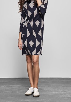 Robe à mi-mollet en bleu marine avec un grand motif géométrique gris clair. Fabriquée en tissu doux, elle présente une coupe décontractée et un col rond.