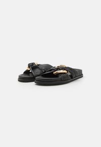 Black flat sandals featuring a smooth leather upper, woven texture, gold hardware accents, and a flexible rubber sole.