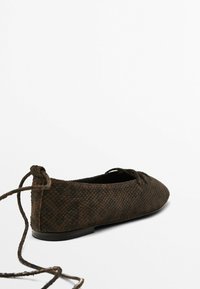 Scarpa piatta marrone realizzata in materiale texture con un motivo geometrico, dotata di punta arrotondata e lacci sul retro.