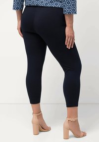 Marina leggings gjorda av elastisk tyg, med hög midja och en slät yta, kombinerade med ljusfärgade plattforms sandaler.