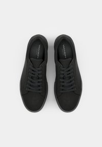Μαύρα αθλητικά παπούτσια με κορδόνια, φτιαγμένα από λείο υλικό με στρογγυλή μύτη και υφασμένο καουτσούκ, διαθέτοντας μινιμαλιστικό σχέδιο και διακριτική σήμανση.
