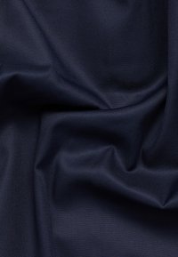 Tmavě modrá látka s hladkým, mírně texturovaným vzhledem, vykazující jemné linie a záhyby, typické pro syntetické materiály.