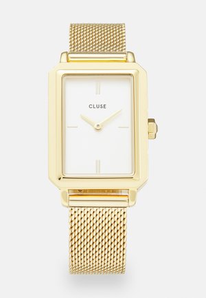 Relógio retangular dourado com um mostrador branco, marcadores de horas minimalistas e uma bracelete de malha metálica. Apresenta uma coroa lateral para ajustar a hora.