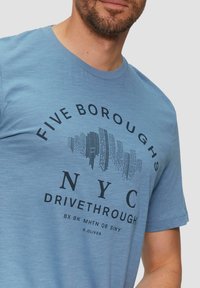 Lichtblauwe katoenen T-shirt met een ronde halslijn, korte mouwen en zwarte grafische tekst: "FIVE BOROUGHS NYC DRIVETHROUGH."
