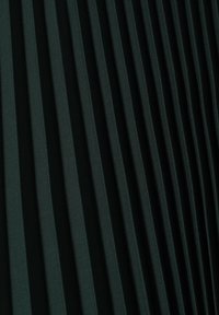 Tessuto verde scuro a pieghe che mostra pieghe verticali, una texture liscia, modelli uniformi e una leggera lucentezza sulla superficie.