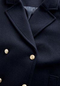 Marineblauwe wollen blazer met goudkleurige knopen, een bladkraag met inkeping en twee klepzakken aan de voorkant. Gestructureerde stof met een gladde binnenvoering.