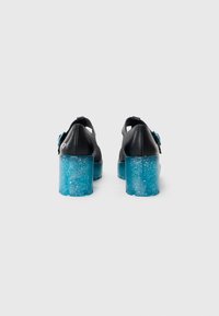 Chaussures en cuir noir avec un talon block chatoyant bleu translucide. L'arrière présente un design ouvert et un accent décoratif.