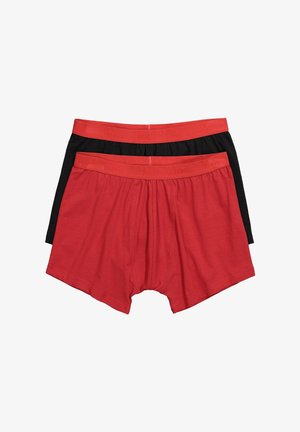 Kaksi paria miesten bokserishortseja, yksi punainen ja yksi musta, molemmissa punaiset joustovyötäröt, aseteltu tasaiseksi valkoiselle taustalle.