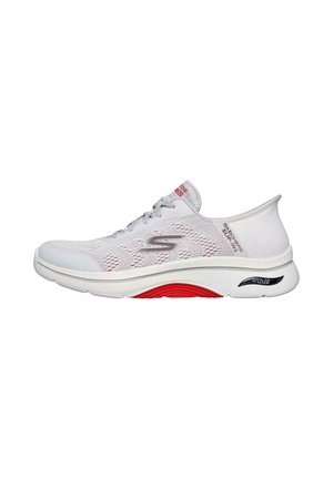 Zapatilla deportiva blanca con parte superior de malla, acentos grises, punta redonda, suela blanca gruesa con detalles en rojo y negro, y un sistema de cordones visible.