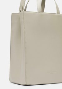 Beżowa skórzana torba tote o strukturalnym, prostokątnym kształcie. Posiada minimalne szwy i wytłoczony logo. Gładka tekstura z parami uchwytów.
