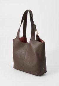Brown leather tote bag with a textured surface, open top, and two shoulder straps. Interior features a contrasting red lining. Gold hardware accent.