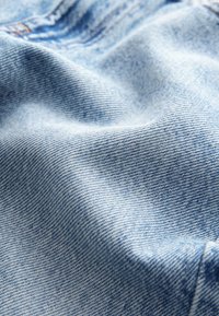 Hellblauer Denim-Stoff mit feiner Struktur und klassischem Köpermuster, ausgestattet mit einer glatten Oberfläche und sanften Falten.