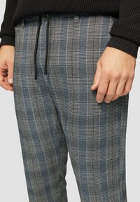 Karierte Lounge-Hose in Blau und Grau, mit einem Kordelzugbund und einer weichen Textur. Nahaufnahme zeigt die Muster-Details und die Passform.