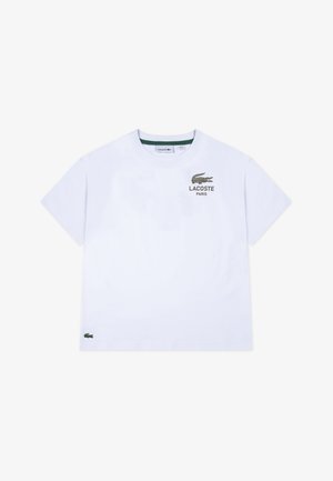 Bela kratka majica s kratkimi rokavi z zelenim logotipom Lacoste in napisem "PARIS" na prsih. Ima klasičen okrogel izrez in stranski logotip.