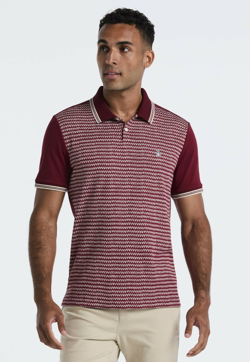 Bordeaux polo met een patroontextuur, contrasterende kraag en mouwstrepen, en een klein logo op de borst. Korte mouwen, aansluitend ontwerp.