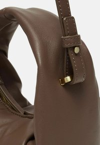 Borsa a tracolla in pelle marrone con superficie texturizzata, un accento in metallo dorato, una tracolla cucita e una tasca laterale con zip.