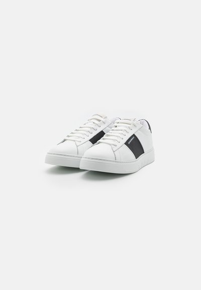 Vita sneakers med en slät läderfinish, med en svart sidopanel, snörningsdesign och en strukturerad vit gummisula.