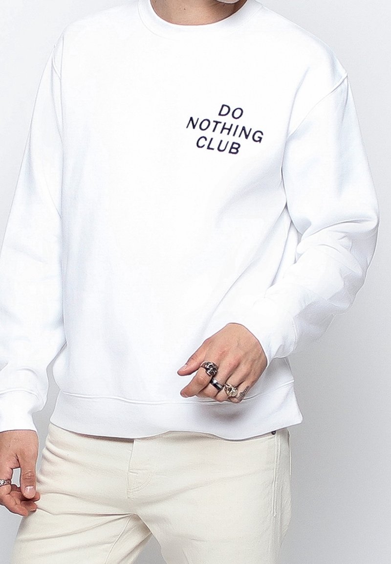 Bílá mikina s výšivkou "DO NOTHING CLUB" v tmavě modré barvě. Má kulatý výstřih, dlouhé rukávy a žebrované manžety. Hladká textura.