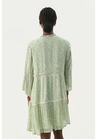 Rochie verde cu motive florale, cu mâneci trei sferturi, design cu straturi, dantelă la talie și margine ondulată. Material ușor.