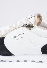 Bílé sportovní boty s černými semišovými akcenty, kovovými tanovými panely a bílými tkaničkami. Na boku se nachází logo "Pepe Jeans London".